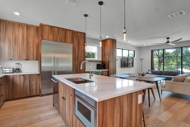 1914 E 8th St, Austin, TX 78702 - kitchen featuring built in appliances, brown cabinetry, light wood-style flooring, open floor plan, and modern cabinets