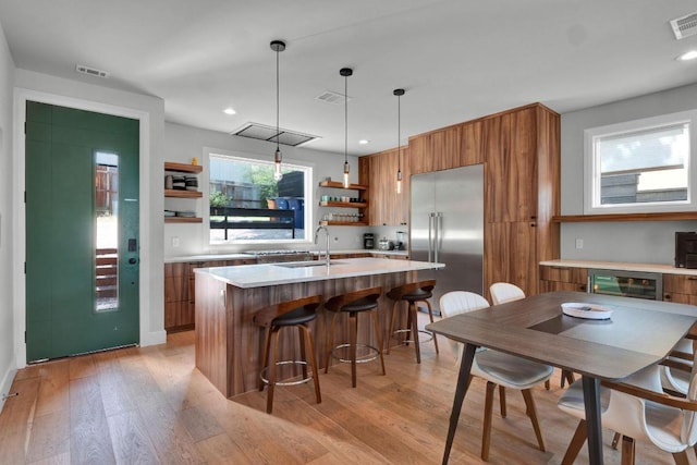 1914 E 8th St, Austin, TX 78702 - kitchen featuring brown cabinetry, stainless steel built in fridge, open shelves, light countertops, and light wood-style flooring