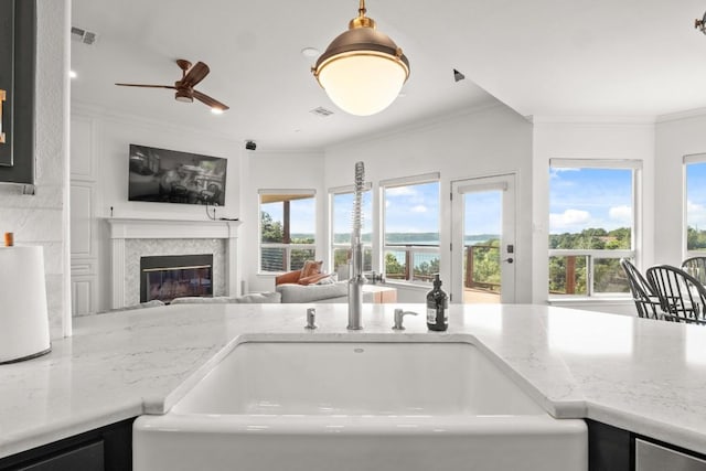 18113 Travis Dr, Lago Vista, TX 78645 - kitchen featuring open floor plan, ornamental molding, plenty of natural light, a glass covered fireplace, and a ceiling fan