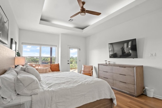 18113 Travis Dr, Lago Vista, TX 78645 - bedroom with access to exterior, light wood finished floors, a tray ceiling, and a ceiling fan