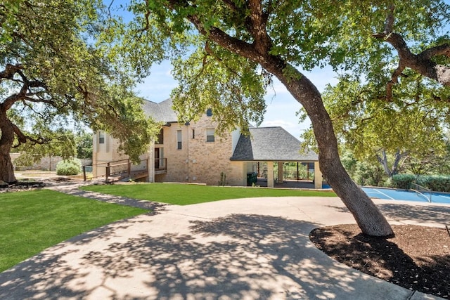 18113 Travis Dr, Lago Vista, TX 78645 - view of front facade with a front yard, a tennis court, roof with shingles, and brick siding