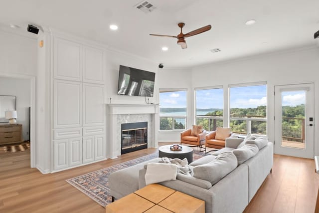 18113 Travis Dr, Lago Vista, TX 78645 - living room with light wood-style flooring, a glass covered fireplace, crown molding, a ceiling fan, and recessed lighting