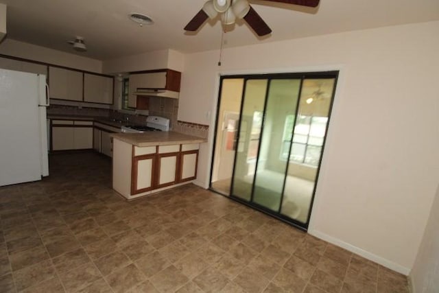 313 Elm St, Copperas Cove, TX 76522 - kitchen featuring freestanding refrigerator, a peninsula, range with gas stovetop, ceiling fan, and under cabinet range hood