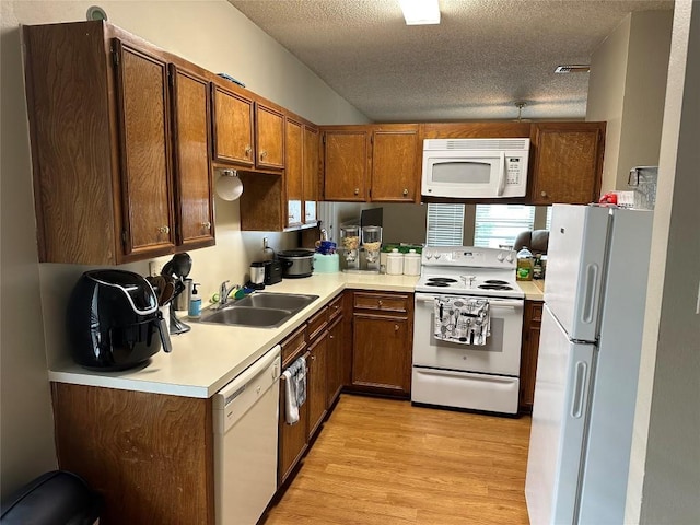 2414 Longview St Unit 301, Austin, TX 78705 - kitchen with white appliances, a textured ceiling, light wood-style flooring, light countertops, and brown cabinetry