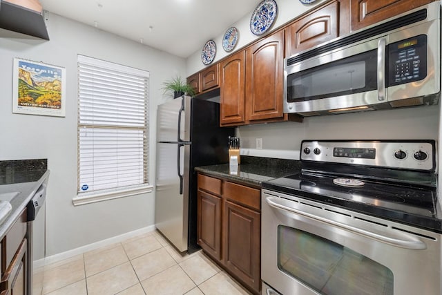 6000 Shepherd Mountain Cv Unit 613, Austin, TX 78730 - kitchen with stainless steel appliances, light tile patterned floors, dark stone countertops, and brown cabinetry