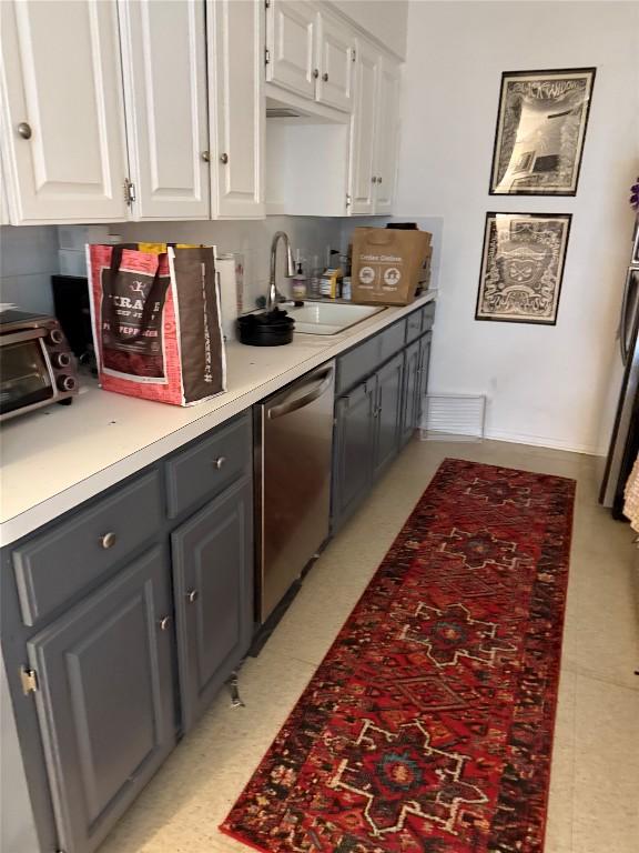 4907 Hawk Cv, Austin, TX 78745 - kitchen with stainless steel dishwasher, white cabinetry, light floors, light countertops, and gray cabinets