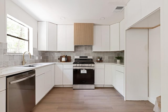 13265 Kerrville Folkway Dr, Austin, TX 78729 - kitchen featuring stainless steel appliances, light countertops, backsplash, and white cabinets