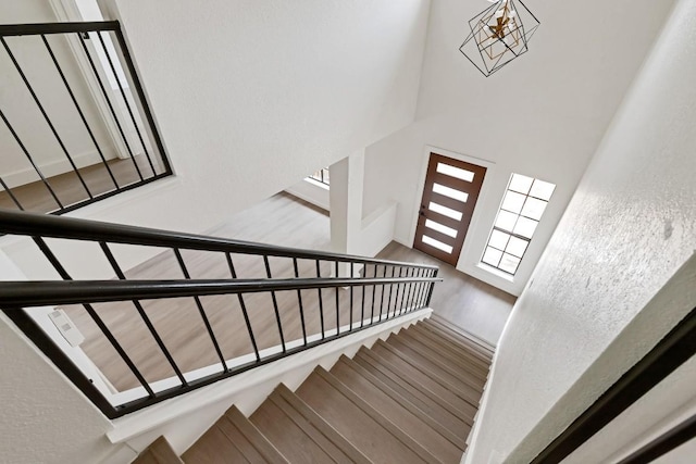 13265 Kerrville Folkway Dr, Austin, TX 78729 - stairway with wood finished floors, a towering ceiling, and a chandelier