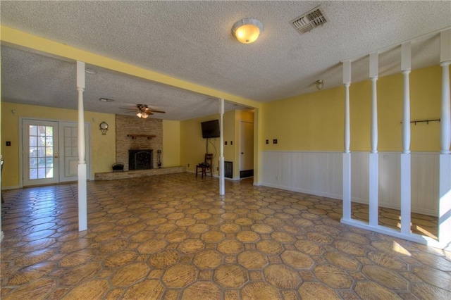 1811 Lone Oak Dr, Leander, TX 78641 - unfurnished living room featuring ceiling fan, a fireplace, a textured ceiling, and a wainscoted wall