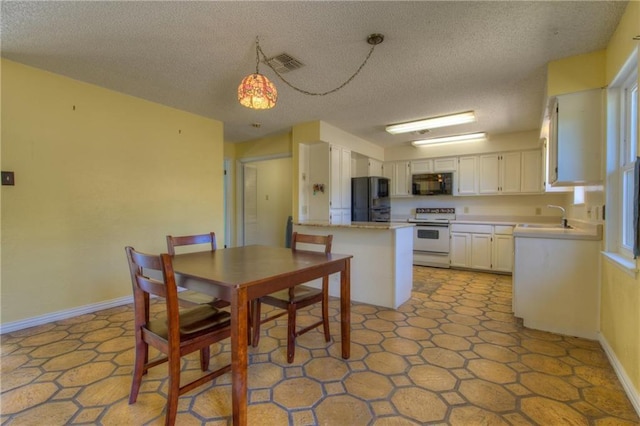 1811 Lone Oak Dr, Leander, TX 78641 - kitchen with black appliances, light countertops, white cabinets, a textured ceiling, and a peninsula