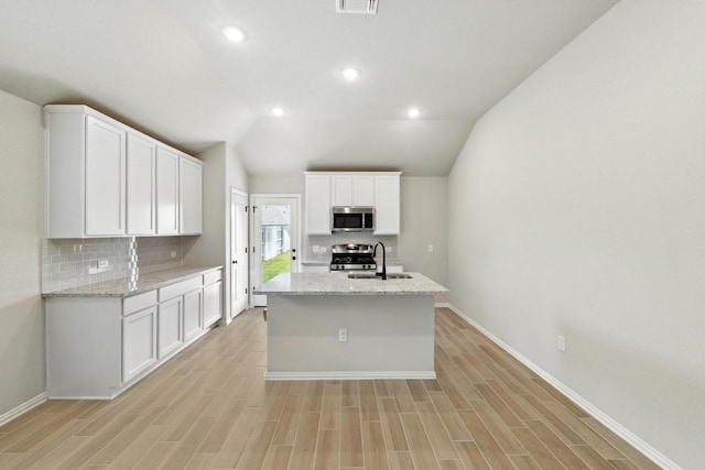 149 Hackberry Ln, Bastrop, TX 78602 - kitchen featuring stainless steel appliances, tasteful backsplash, white cabinetry, an island with sink, and lofted ceiling