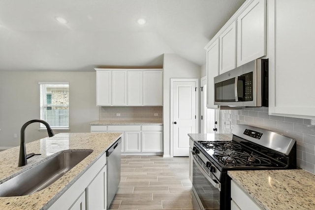 149 Hackberry Ln, Bastrop, TX 78602 - kitchen with appliances with stainless steel finishes, lofted ceiling, white cabinets, decorative backsplash, and recessed lighting