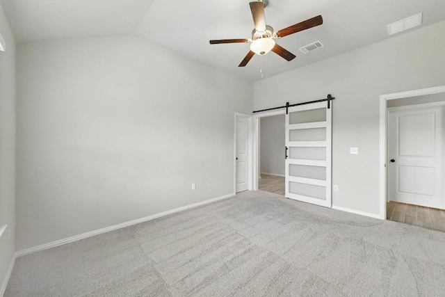 149 Hackberry Ln, Bastrop, TX 78602 - unfurnished bedroom with carpet floors, a barn door, ceiling fan, and lofted ceiling