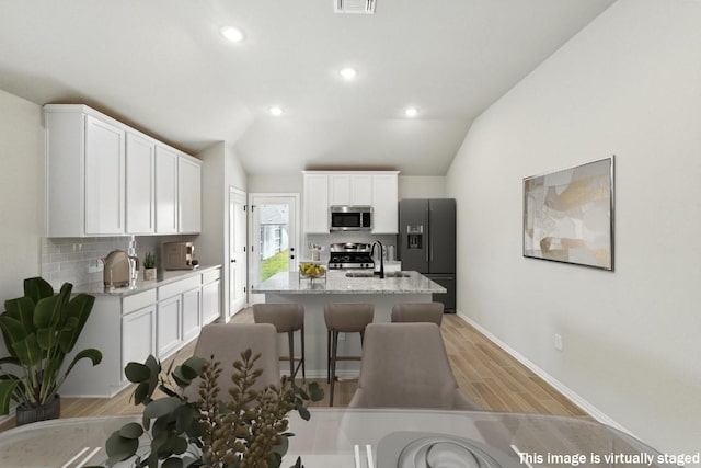 149 Hackberry Ln, Bastrop, TX 78602 - kitchen with appliances with stainless steel finishes, decorative backsplash, light wood-style flooring, light stone countertops, and lofted ceiling