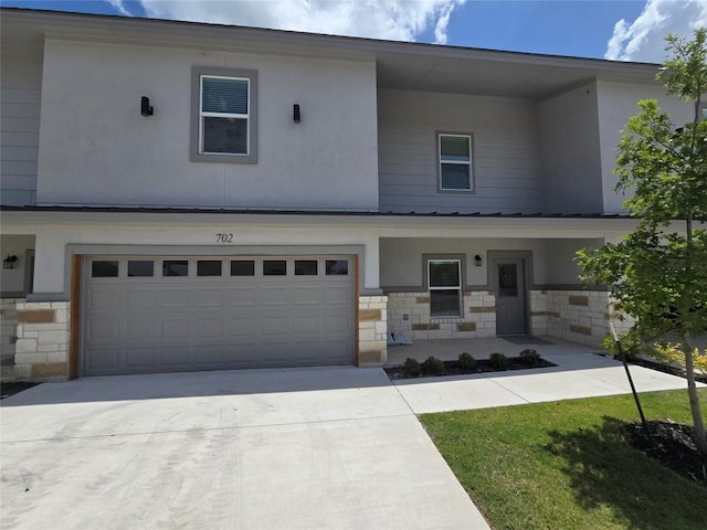 2105 Tiger Trl Unit 702, Round Rock, TX 78664 - view of front of home featuring an attached garage, stone siding, covered porch, driveway, and stucco siding