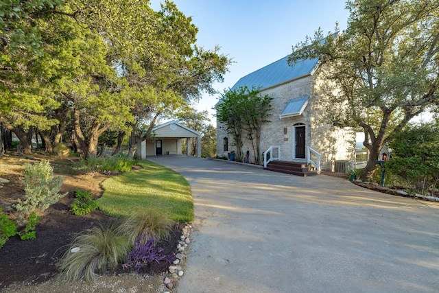 8132 Breeze Way, Jonestown, TX 78645 - view of front of home featuring concrete driveway, stone siding, a metal roof, and an attached carport