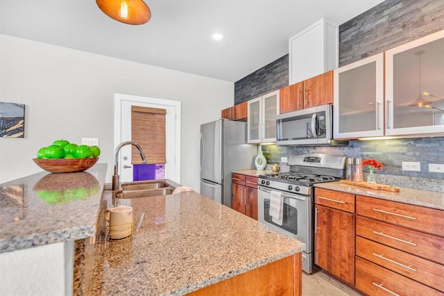 5325 Sendero Hills Pkwy, Austin, TX 78724 - kitchen with stainless steel appliances, brown cabinetry, light stone counters, tasteful backsplash, and recessed lighting
