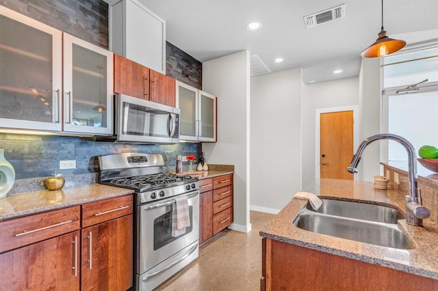 5325 Sendero Hills Pkwy, Austin, TX 78724 - kitchen featuring stainless steel appliances, decorative backsplash, brown cabinetry, light stone countertops, and recessed lighting