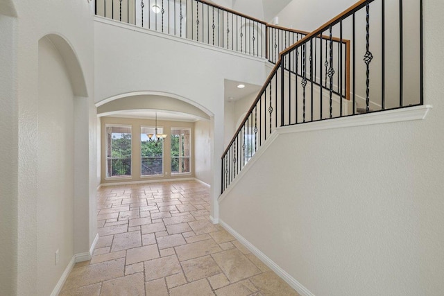 11421 Dona Villa Dr, Austin, TX 78726 - entrance foyer featuring stone tile floors, a chandelier, a high ceiling, stairway, and arched walkways
