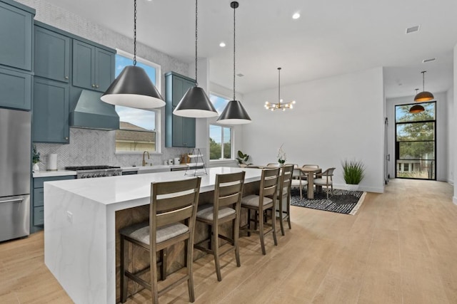 21408 Lakefront Dr, Lago Vista, TX 78645 - kitchen with freestanding refrigerator, light countertops, a center island with sink, backsplash, and a chandelier