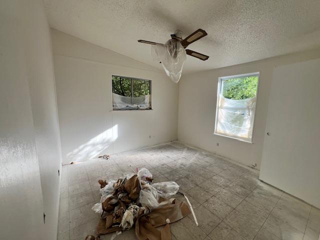908 Glass Dr, Leander, TX 78641 - empty room with plenty of natural light, ceiling fan, a textured ceiling, and vaulted ceiling
