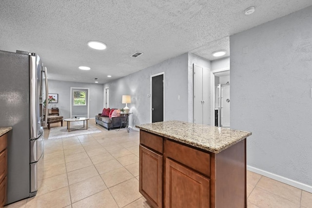 8 Spalding Cir, Wimberley, TX 78676 - kitchen with freestanding refrigerator, light tile patterned floors, a textured wall, a textured ceiling, and light stone counters