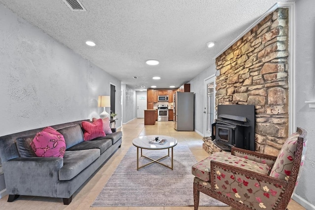 8 Spalding Cir, Wimberley, TX 78676 - living room with a wood stove, a textured ceiling, recessed lighting, and light tile patterned flooring