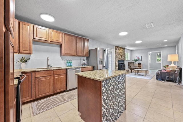8 Spalding Cir, Wimberley, TX 78676 - kitchen featuring stainless steel appliances, a textured ceiling, open floor plan, a kitchen island, and light stone countertops