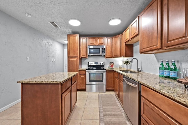 8 Spalding Cir, Wimberley, TX 78676 - kitchen featuring stainless steel appliances, a textured wall, a textured ceiling, light stone counters, and brown cabinetry