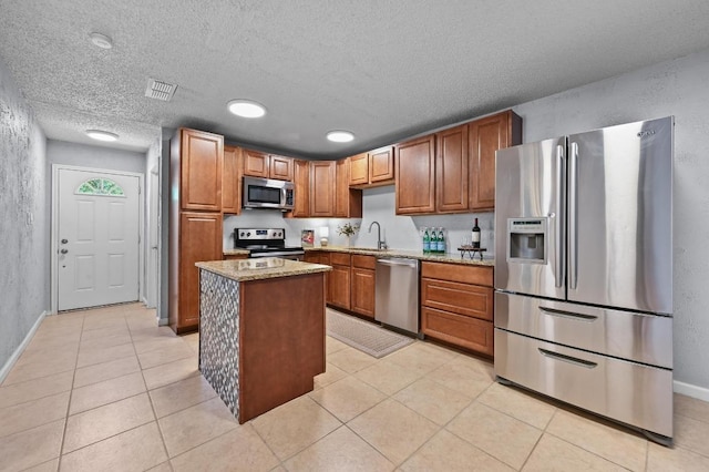 8 Spalding Cir, Wimberley, TX 78676 - kitchen with stainless steel appliances, light stone counters, light tile patterned flooring, a kitchen island, and a textured ceiling