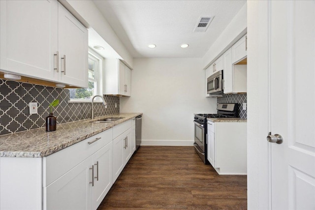 2701 Coatbridge Dr, Austin, TX 78745 - kitchen featuring appliances with stainless steel finishes, recessed lighting, dark wood finished floors, backsplash, and white cabinets