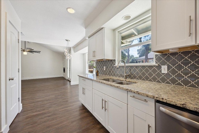 2701 Coatbridge Dr, Austin, TX 78745 - kitchen with stainless steel dishwasher, backsplash, white cabinets, dark wood-style floors, and vaulted ceiling