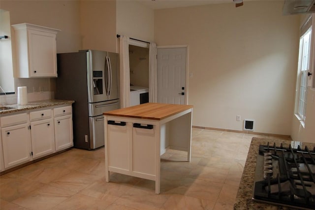 12615 Dove Valley Trl, Austin, TX 78729 - kitchen with stainless steel fridge, wood counters, white cabinets, washer / clothes dryer, and a kitchen island