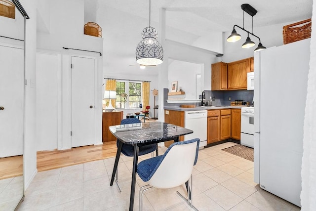 11901 Swearingen Dr Unit 43-I, Austin, TX 78758 - kitchen featuring white appliances, light tile patterned floors, high vaulted ceiling, decorative light fixtures, and brown cabinetry