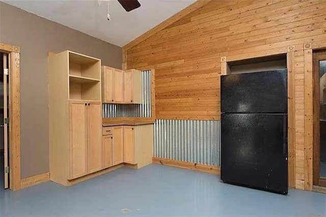 4901 County Road 210, Bertram, TX 78605 - kitchen with lofted ceiling, wood walls, ceiling fan, freestanding refrigerator, and concrete floors