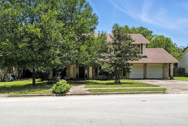 7314 Danwood Dr, Austin, TX 78759 - view of property hidden behind natural elements featuring stone siding, driveway, a front lawn, and a garage