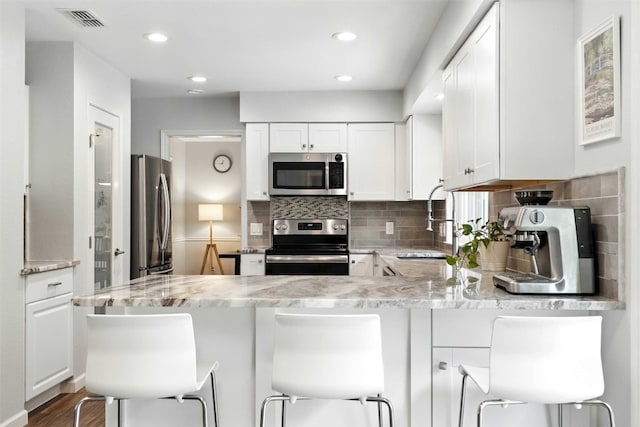 7314 Danwood Dr, Austin, TX 78759 - kitchen featuring appliances with stainless steel finishes, white cabinetry, a peninsula, decorative backsplash, and recessed lighting
