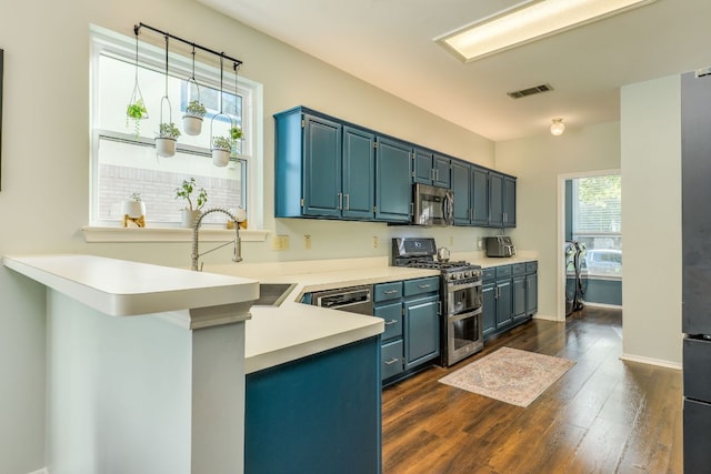 1104 Woodhollow Ln, Cedar Park, TX 78613 - kitchen with appliances with stainless steel finishes, dark wood finished floors, light countertops, a peninsula, and blue cabinets