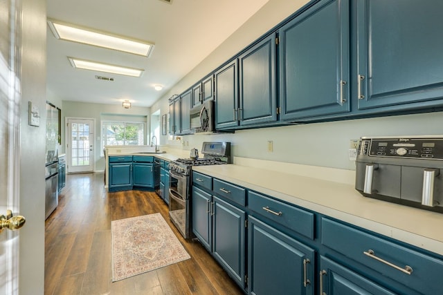 1104 Woodhollow Ln, Cedar Park, TX 78613 - kitchen featuring appliances with stainless steel finishes, dark wood-type flooring, blue cabinetry, and light countertops