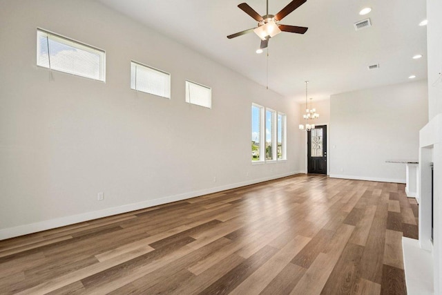 181 Benedum Way, Liberty Hill, TX 78642 - unfurnished living room with a chandelier, a ceiling fan, a high ceiling, wood finished floors, and recessed lighting