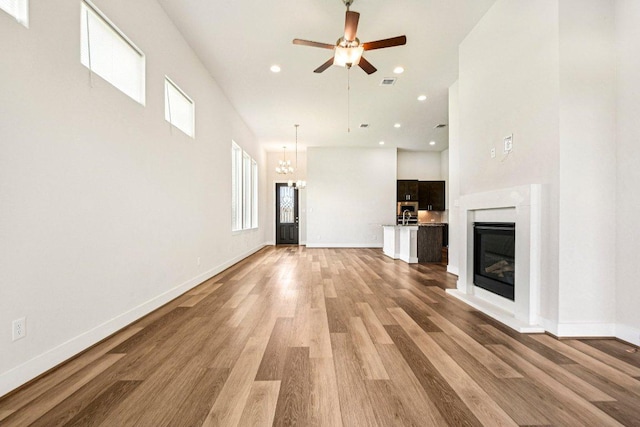 181 Benedum Way, Liberty Hill, TX 78642 - unfurnished living room with a ceiling fan, light wood-type flooring, a chandelier, recessed lighting, and a glass covered fireplace