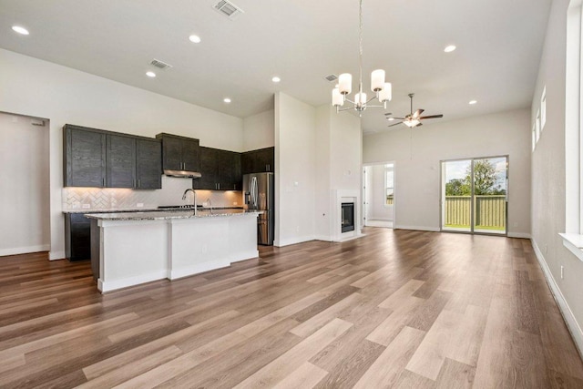 181 Benedum Way, Liberty Hill, TX 78642 - kitchen with a chandelier, open floor plan, stainless steel fridge, a kitchen island with sink, and decorative backsplash