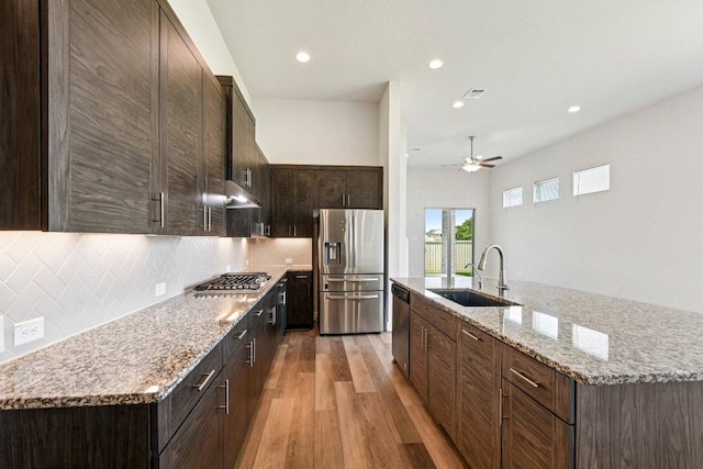 181 Benedum Way, Liberty Hill, TX 78642 - kitchen with light wood-style flooring, appliances with stainless steel finishes, backsplash, a ceiling fan, and dark brown cabinets