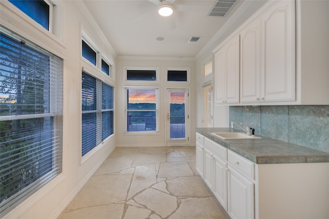 24205 State Highway 71 W, Spicewood, TX 78669 - kitchen with ceiling fan, white cabinets, tasteful backsplash, light stone finish floors, and ornamental molding