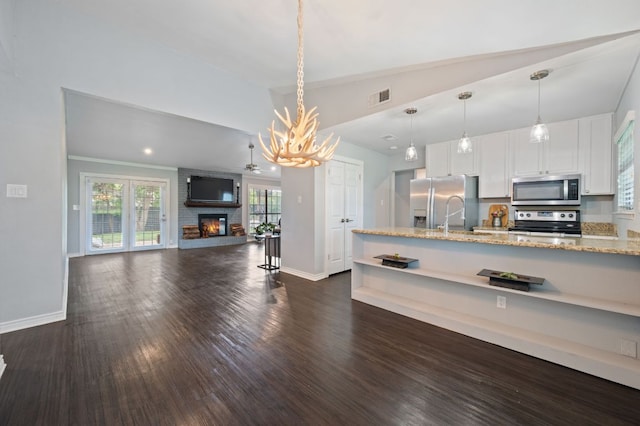 4310 Ponderosa Ln, Temple, TX 76502 - kitchen with stainless steel appliances, light stone countertops, white cabinets, lofted ceiling, and decorative light fixtures