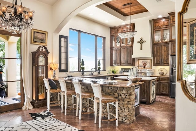 601 Strada Luca, Florence, TX 76527 - bar area featuring arched walkways, a high ceiling, wall chimney exhaust hood, hanging light fixtures, and stainless steel fridge with ice dispenser