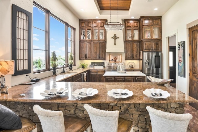 601 Strada Luca, Florence, TX 76527 - kitchen with stainless steel fridge with ice dispenser, a center island, a peninsula, glass insert cabinets, and light stone counters