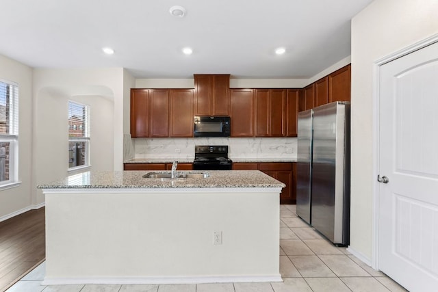 633 Weizenbock Ln, Austin, TX 78728 - kitchen with black appliances, tasteful backsplash, light stone counters, a center island with sink, and recessed lighting