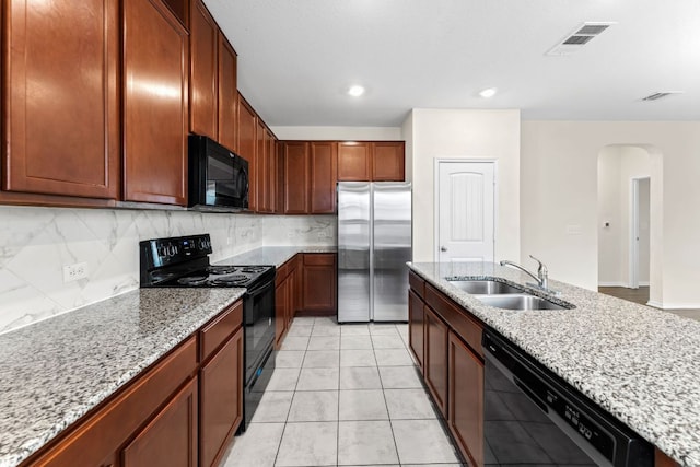 633 Weizenbock Ln, Austin, TX 78728 - kitchen featuring black appliances, arched walkways, decorative backsplash, light stone countertops, and recessed lighting