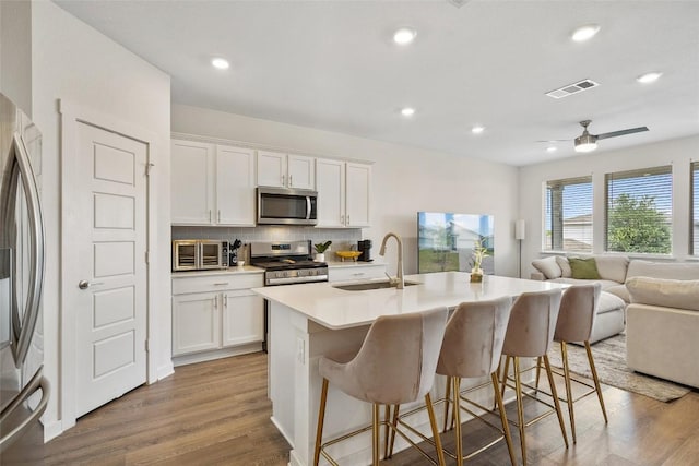 13821 Zuhause Dr, Pflugerville, TX 78660 - kitchen with white cabinetry, backsplash, a breakfast bar area, light wood-style floors, and recessed lighting